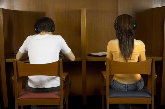学生在图书馆学习时用耳机听音乐