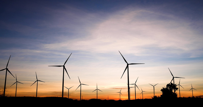 风车农场和日落背景中带有叶片的大型风力涡轮机的轮廓