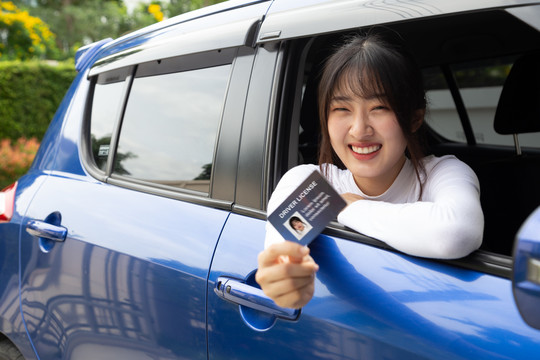 迷人的亚洲年轻女子自豪地展示驾照