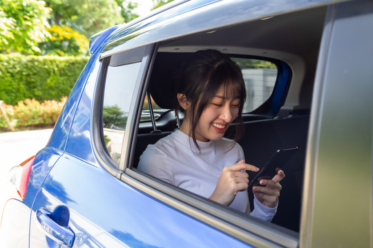 亚洲青少年女性在汽车后座使用智能手机，乘客使用应用程序预订乘车和点对点乘车共享概念