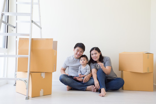 在搬家日，快乐亚洲家庭在新房子里装着纸板箱，房地产和家居概念