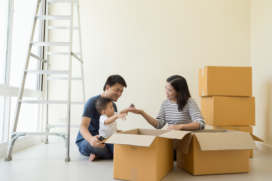 在搬家日，快乐亚洲家庭在新房子里装着纸板箱，房地产和家居概念