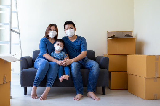 亚洲家庭戴2019冠状病毒疾病预防罩，在搬迁日和新家搬迁。搬家与房地产新概念