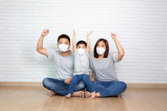 亚洲家庭戴2019冠状病毒疾病预防罩，并在家里手举、坐在一起。保护家庭免受空气污染概念