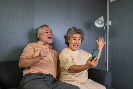 亚洲老年夫妇通过手机视频通话聊天、老年智能技术和在线行动保持联系的概念