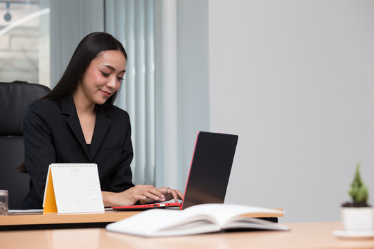 一位亚洲女商人在办公室使用笔记本电脑的照片