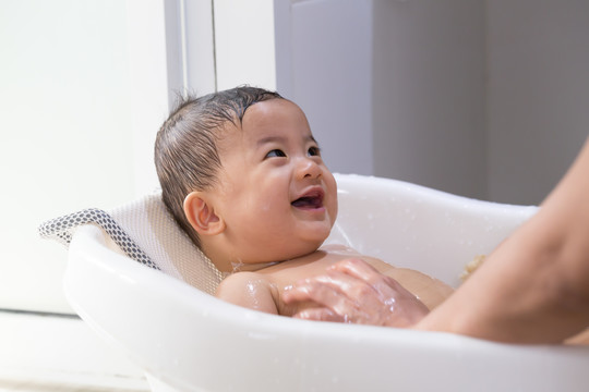 妈妈正在洗澡的亚洲男婴。幼儿卫生及护理概念