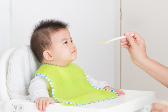 母亲为快乐的亚洲男婴喂食