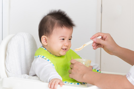 母亲为快乐的亚洲男婴喂食