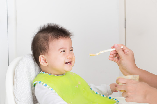 母亲为快乐的亚洲男婴喂食