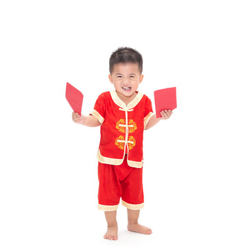 亚洲男婴站着拿着红包的肖像，白色背景上隔离着中国传统服装，为中国新年概念装扮，一岁六个月婴儿模型