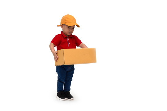 快乐儿童亚洲男孩送货员，戴着黄色帽子，穿着红色衬衫，站在白色背景下，包裹邮筒被隔离，两岁一个月大