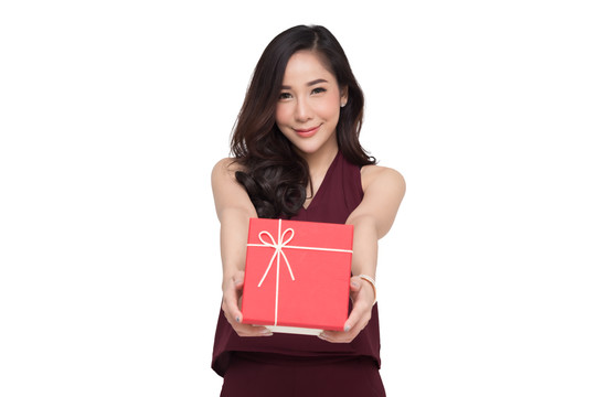 快乐美丽的亚洲女人微笑着，白色背景上隔着一个红色的礼盒。少女坠入爱河，接受情人的礼物。新年、圣诞节和