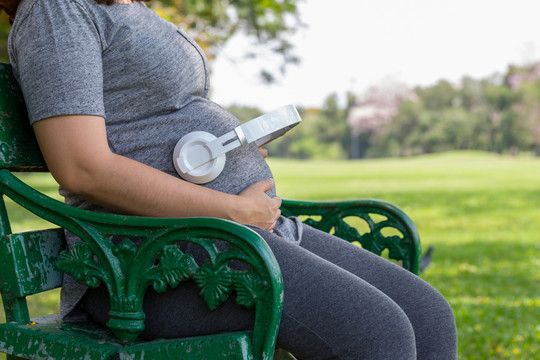 孕妇在公园听音乐，坐在椅子上
