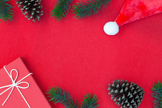 圣诞构图俯视图、礼品盒、松果、红色背景上的冷杉枝以及文本信息的复制空间