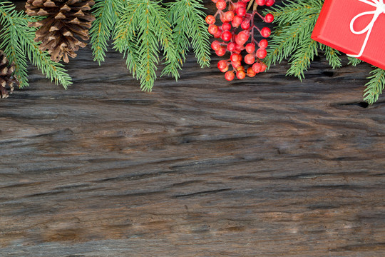 圣诞和新年快乐构图的俯视图、礼品盒、松果、木质背景上的杉木树枝以及文本的复制空间