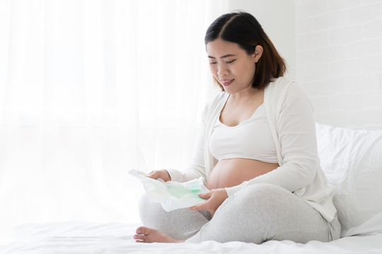 亚洲孕妇为宝宝选择尿布尺寸，为新生儿做计划