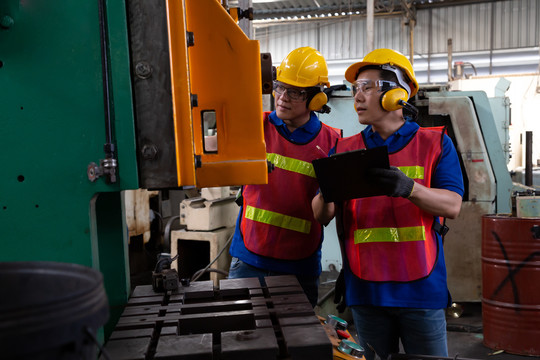亚洲工厂工程师戴黄色安全帽检查机器，年度维护概念