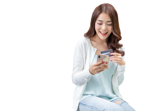 亚洲女性使用白色背景的信用卡和智能手机在线购物