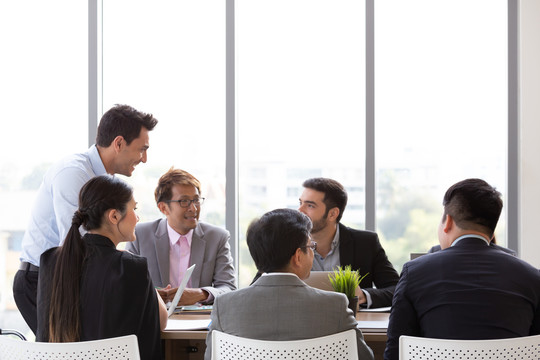 团队会议期间，首席商人站在会议桌旁，创业者在团队谈判中开始合作团队合作