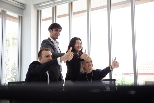 成功的商务人士竖起大拇指，面带微笑，完美的合作团队理念