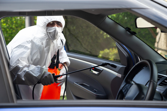 2019冠状病毒疾病患者佩戴PPE套件杀死汽车内的细菌和病毒，COVID-19在汽车概念中的消毒和清