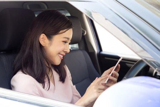 亚洲女性在最后一个假期开车旅行后，使用手机并享受与朋友群的信息交流