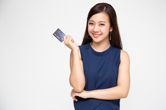 年轻的亚洲女士面带微笑，手持信用卡，背景为白色
