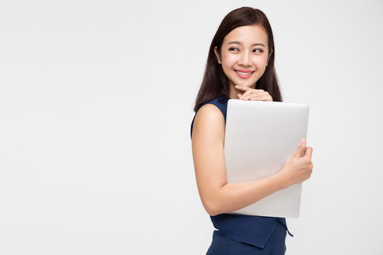 快乐的亚洲女商人手持笔记本电脑，在白色背景下看着别处