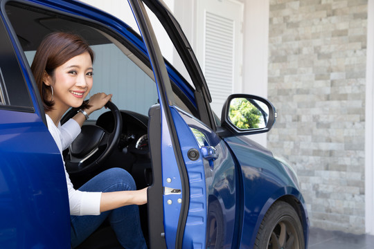 年轻的亚洲女性在房前停车后从汽车或敞篷车里出来