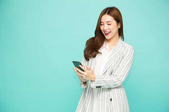 快乐的年轻亚洲女性使用智能手机，在绿色背景下的手机聊天应用程序上收到来自消息的好消息