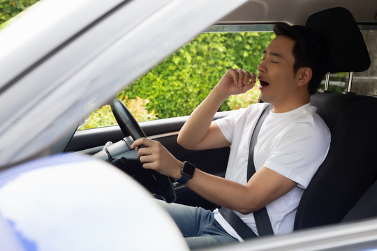 疲惫的年轻人睡在车里，辛苦的工作会导致身体不好，在红灯、交通堵塞或工作过度时坐着睡觉