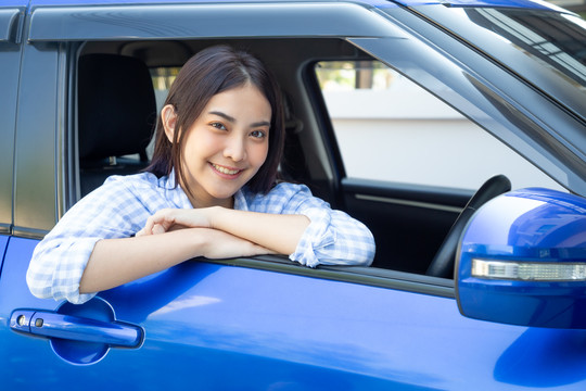 亚洲女性在开车旅行的过程中，开心地微笑着，带着快乐的积极表情，人们享受着欢笑的交通和免下车的概念