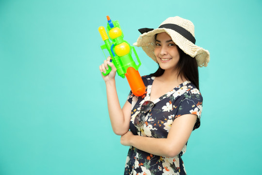 在泰国的泼水节上，一位年轻的亚洲美女手持塑料水枪，被隔离在绿色背景下