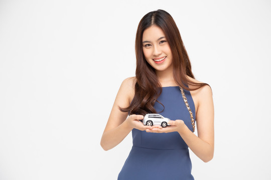 亚洲女性手持白色背景隔离车型，旅行保险理念