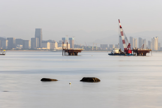 晨光中海上建设施工的起重机