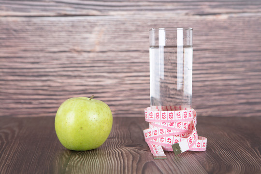 一个苹果和被尺子缠绕的一瓶水