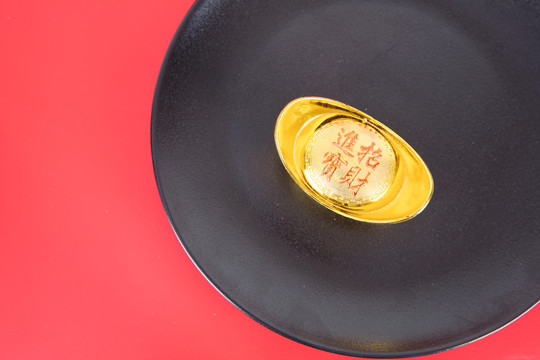 红背景上黑色盘子里的金元宝