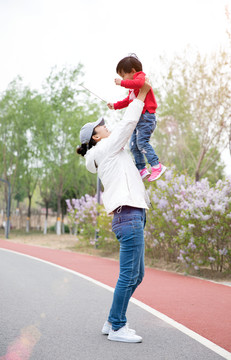 公园里年轻妈妈把女儿举过头顶