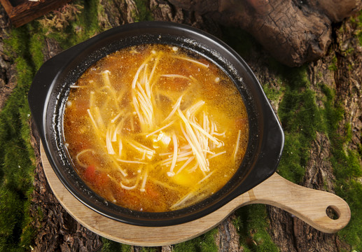 木板上放着一盘金针菇汤