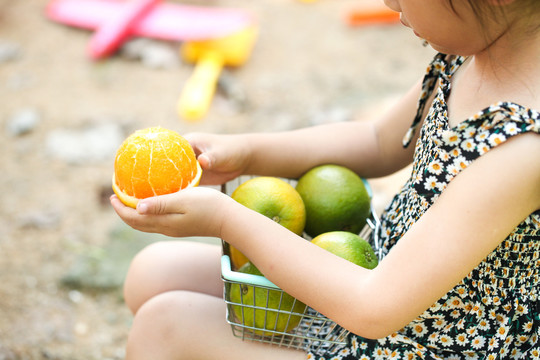 小女孩小手里拿着夏橙