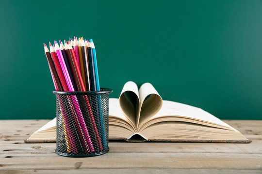 折成心形的书和装满笔筒的彩铅笔