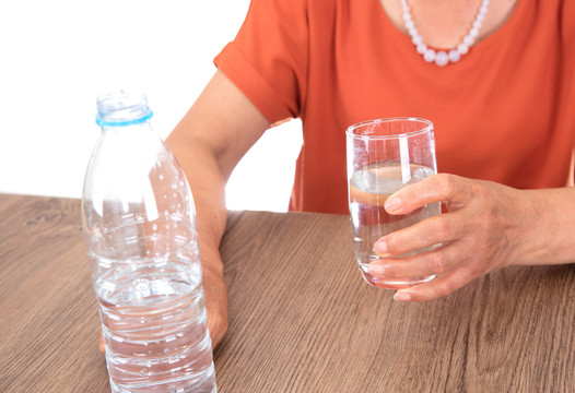 白背景前桌子旁的女性正要喝水