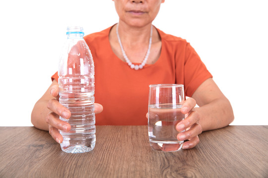 白背景前桌子旁的女性正要喝水