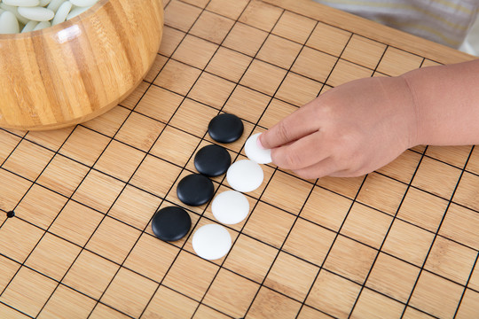 手拿着棋子在围棋棋盘上下棋