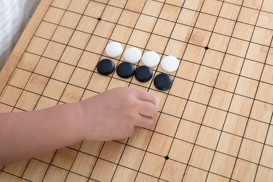 手拿着棋子在围棋棋盘上下棋