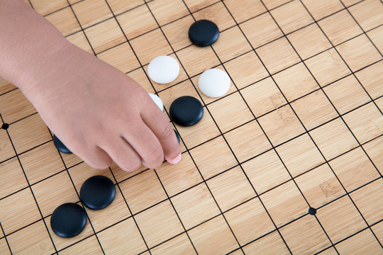 手拿着棋子在围棋棋盘上下棋