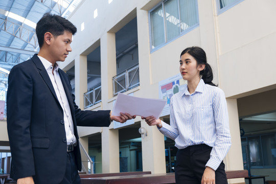 女人从一个男人那里拿到文件去修改。