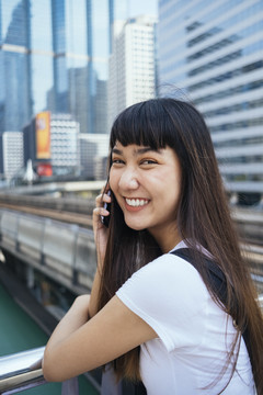 年轻的泰国女人在智能手机上聊天，幸福地微笑的照片。