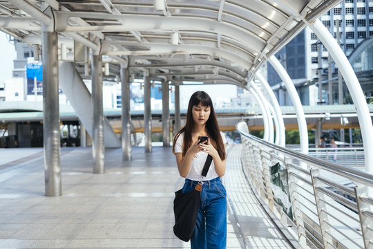 可爱的年轻泰国潮人使用手机，在城市中旅行